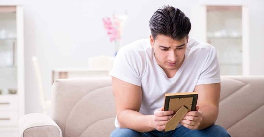 A man looking at a picture of someone. He appears sad and alone.