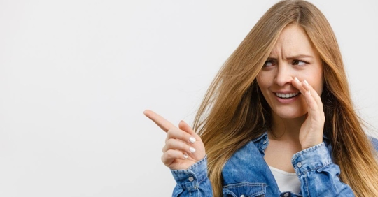 A woman points over at someone while whispering toward someone else