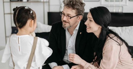 A daughter looking at her mother and father, who are about to tell her something
