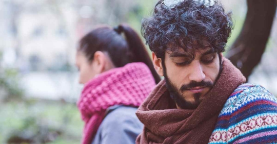 A man and woman sitting next to each other but looking away from each other