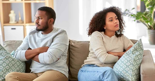 A man and woman sitting on a couch looking away from each other