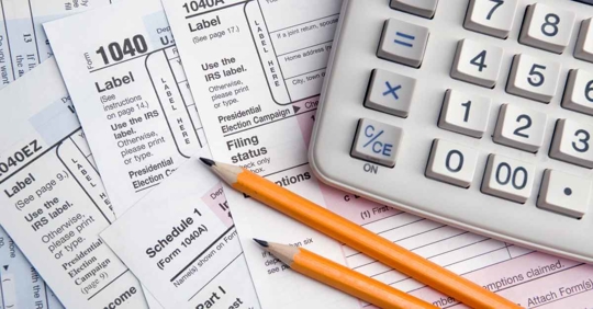 A calculator, pencils, and 1040 tax forms