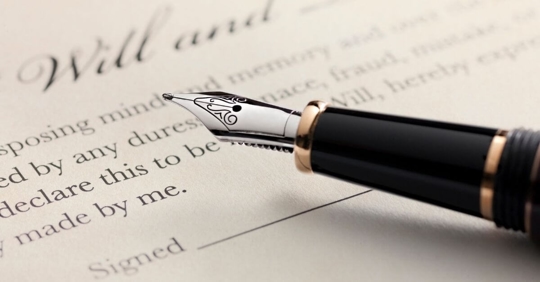 An old-fashioned pen resting on a document that says "Will"