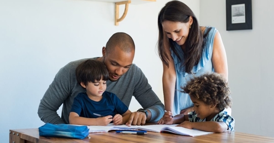 interracial couple helping two children with homework