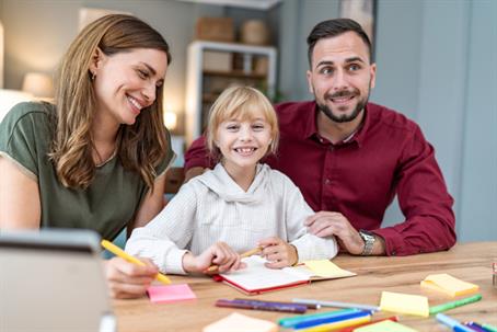 parents sitting at an office desk with their daughter between them
