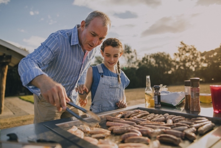 father and daughter grilling sausages